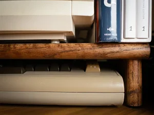 A desk level photo of the right front half of a C64 in a hutch under a monitor.