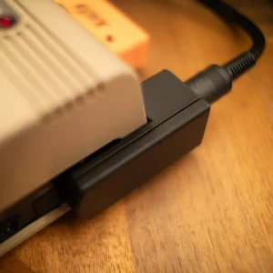 An angled top down view of a Commodore 64 using a right-angle power adapter.