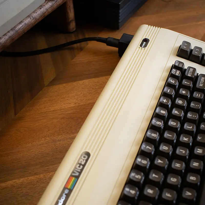 A Commodore VIC-20 computer seen from above left with a right-angle power adapter installed.