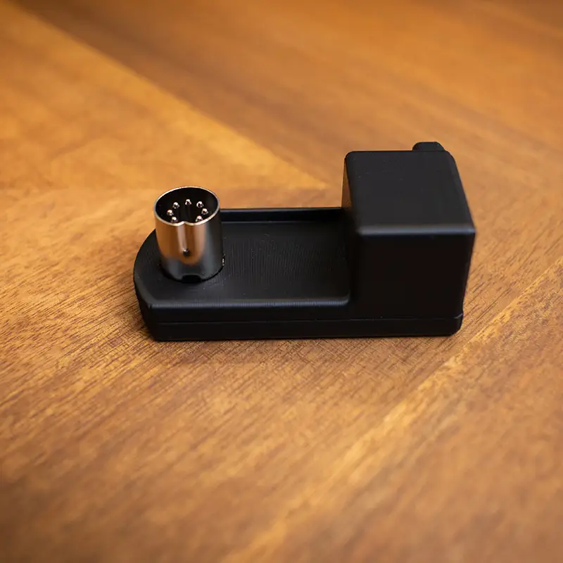Side view of a Commodore 64C right-angle power adapter sitting on a desk.