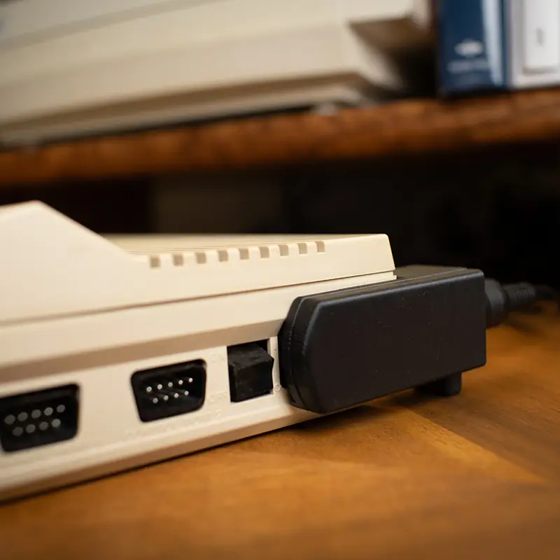 A side of a Commodore 64C with a right-angle power adapter in place.