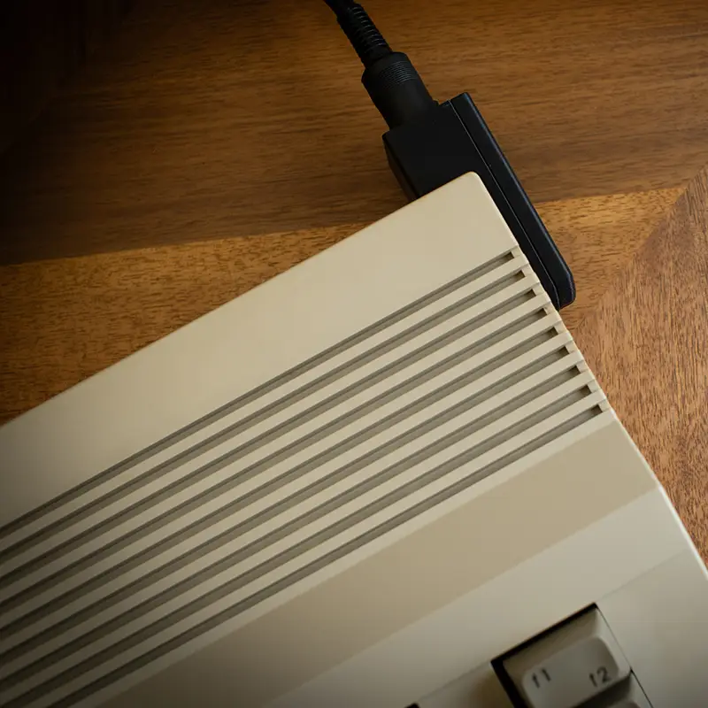 Top view of a Commodore 64C computer with a power cable plugged into a right-angle power adapter.